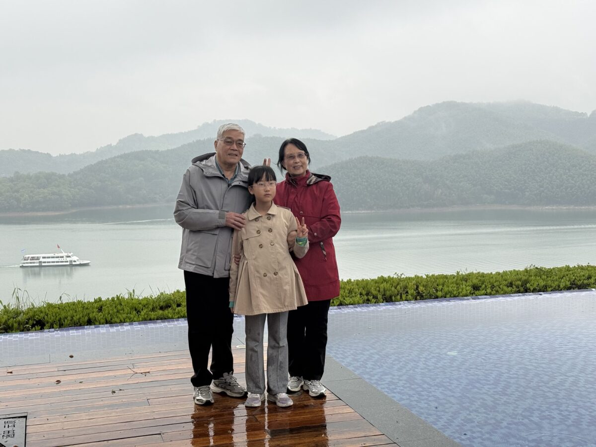 悦杉在奶奶背后比兔耳朵 / Yueshan pulling bunny ears behind Grandma — the mischief shot
