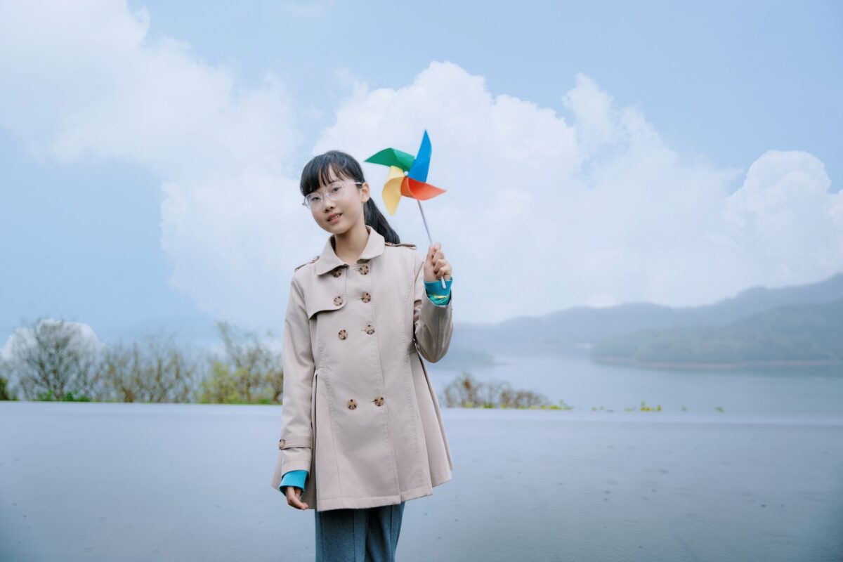 悦杉拿着彩色风车，天目湖背景 / Yueshan with a colorful pinwheel, Tianmu Lake behind