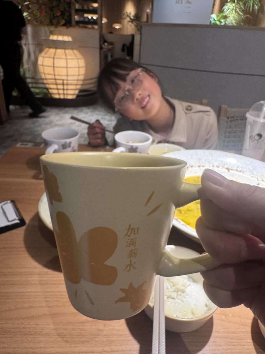 悦杉举着"加满薪水"的杯子 / Yueshan with her "top up the salary" cup, grinning